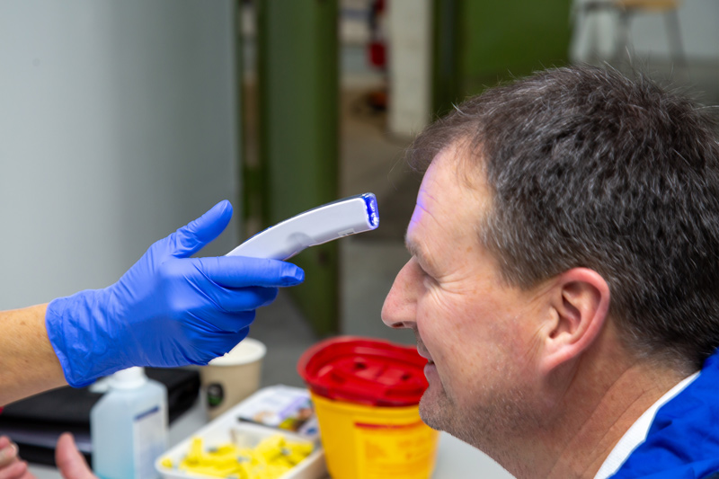 Auf dem Bild ist zu sehen, wie bei dem Spendenwilligen die Körpertemperatur gemessen wird.